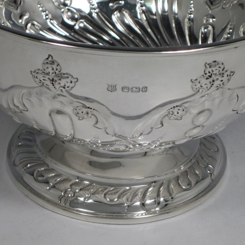 Antique Victorian sterling silver rose bowl, having a round hand-chased body with swirl fluted and floral decoration, and sitting on a pedestal foot. Made by the Deakin Brothers of Sheffield in 1897. The dimensions of this fine hand-made silver bowl are height 12 cms (4.75 inches), diameter 19.5 cms (7.75 inches), and it weighs approx. 391g (12.6 troy ounces).   