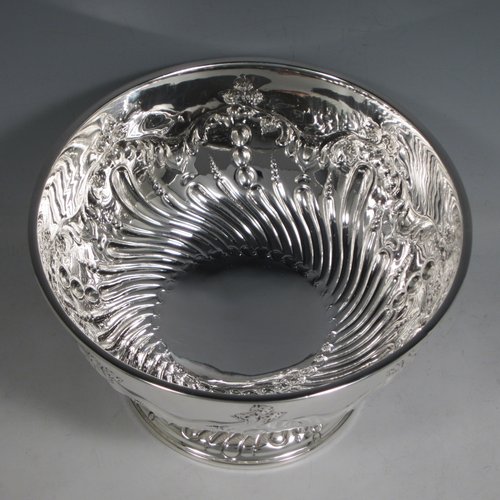 Antique Victorian sterling silver rose bowl, having a round hand-chased body with swirl fluted and floral decoration, and sitting on a pedestal foot. Made by the Deakin Brothers of Sheffield in 1897. The dimensions of this fine hand-made silver bowl are height 12 cms (4.75 inches), diameter 19.5 cms (7.75 inches), and it weighs approx. 391g (12.6 troy ounces).   