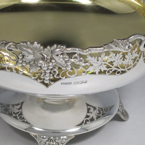 A Sterling silver table bowl, having a round body, with an applied and hand-pierced grape & vine-leaf border, with a gold-gilt interior, all sitting on a hand-pierced pedestal base with four hand-chased feet. Made by Olivant & Botsford of Sheffield in 1937. The dimensions of this fine hand-made silver bowl are diameter 21.5 cms (8.5 inches), height 14 cms (5.5 inches), and it weighs approx. 737g (23.8 troy ounces).   