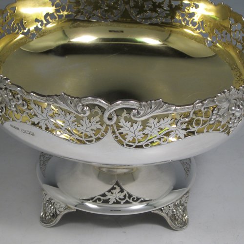 A Sterling silver table bowl, having a round body, with an applied and hand-pierced grape & vine-leaf border, with a gold-gilt interior, all sitting on a hand-pierced pedestal base with four hand-chased feet. Made by Olivant & Botsford of Sheffield in 1937. The dimensions of this fine hand-made silver bowl are diameter 21.5 cms (8.5 inches), height 14 cms (5.5 inches), and it weighs approx. 737g (23.8 troy ounces).   