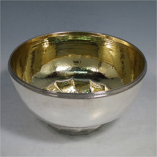 A Sterling Silver Arts and Crafts table bowl, having a round hand-hammered body, with an applied rope-twist border, a gold-gilt interior, and sitting on a swirl-fluted foot with a flat base. Made by Edward Spencer of the Artificers Guild of London in 1927. The dimensions of this fine hand-made Arts & Crafts silver bowl are diameter 16 cms (6.25 inches), height 8.5 cms (3.3 inches), and it weighs approx. 277g (8.9 troy ounces).