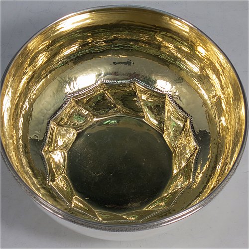 A Sterling Silver Arts and Crafts table bowl, having a round hand-hammered body, with an applied rope-twist border, a gold-gilt interior, and sitting on a swirl-fluted foot with a flat base. Made by Edward Spencer of the Artificers Guild of London in 1927. The dimensions of this fine hand-made Arts & Crafts silver bowl are diameter 16 cms (6.25 inches), height 8.5 cms (3.3 inches), and it weighs approx. 277g (8.9 troy ounces).