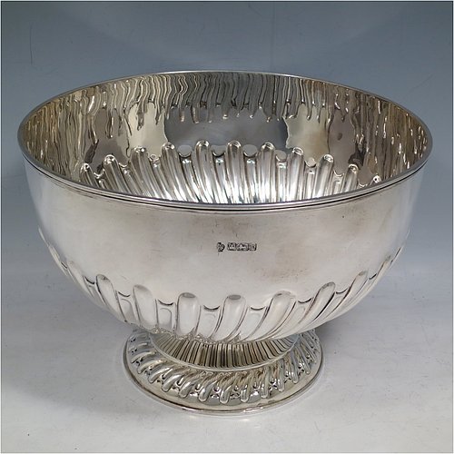 An Antique Edwardian Sterling Silver large table bowl, having a round body with an applied reeded border and hand-chased half swirl-fluted decoration, all sitting on a pedestal foot which is also fluted. Made by William Hutton of Sheffield in 1905. The dimensions of this fine hand-made antique silver table rose bowl are diameter 23.5 cms (9.25 inches), height 16 cms (6.3 inches), and it weighs approx. 616g (19.9 troy ounces).    