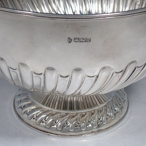 An Antique Edwardian Sterling Silver large table bowl, having a round body with an applied reeded border and hand-chased half swirl-fluted decoration, all sitting on a pedestal foot which is also fluted. Made by William Hutton of Sheffield in 1905. The dimensions of this fine hand-made antique silver table rose bowl are diameter 23.5 cms (9.25 inches), height 16 cms (6.3 inches), and it weighs approx. 616g (19.9 troy ounces).    