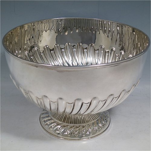 An Antique Edwardian Sterling Silver large table bowl, having a round body with an applied reeded border and hand-chased half swirl-fluted decoration, all sitting on a pedestal foot which is also fluted. Made by William Hutton of Sheffield in 1905. The dimensions of this fine hand-made antique silver table rose bowl are diameter 23.5 cms (9.25 inches), height 16 cms (6.3 inches), and it weighs approx. 616g (19.9 troy ounces).    