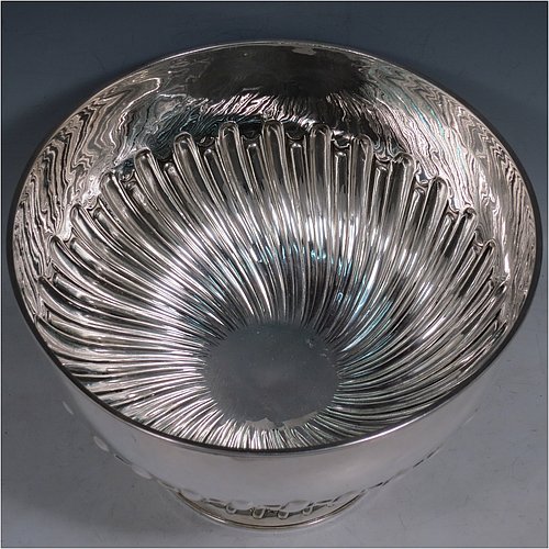 An Antique Edwardian Sterling Silver large table bowl, having a round body with an applied reeded border and hand-chased half swirl-fluted decoration, all sitting on a pedestal foot which is also fluted. Made by William Hutton of Sheffield in 1905. The dimensions of this fine hand-made antique silver table rose bowl are diameter 23.5 cms (9.25 inches), height 16 cms (6.3 inches), and it weighs approx. 616g (19.9 troy ounces).    