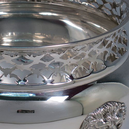 An Antique Victorian Sterling Silver table bowl, having a plain round bellied body with a hand-pierced top gallery border, together with two cast lion-mask and ring side-handles, and sitting on a plain round pedestal foot. Made by Gibson & Langland of London in 1899. The dimensions of this fine hand-made antique silver table bowl are diameter 18 cms (7 inches), height 14 cms (5.5 inches), and it weighs approx. 581g (18.7 troy ounces).    