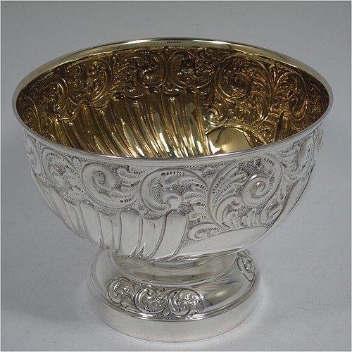 A very pretty Antique Edwardian Sterling Silver bowl, having a round body with hand-chased floral, scroll, and fluted decoration, an applied reeded border and a gold gilt interior, and all sitting on a pedestal foot with matching decoration. Made by William Hutton of Birmingham in 1906. The dimensions of this fine hand-made antique silver bowl are diameter 15 cms (6 inches), height 12 cms (4.75 inches), and it weighs approx. 247g (8 troy ounces). 