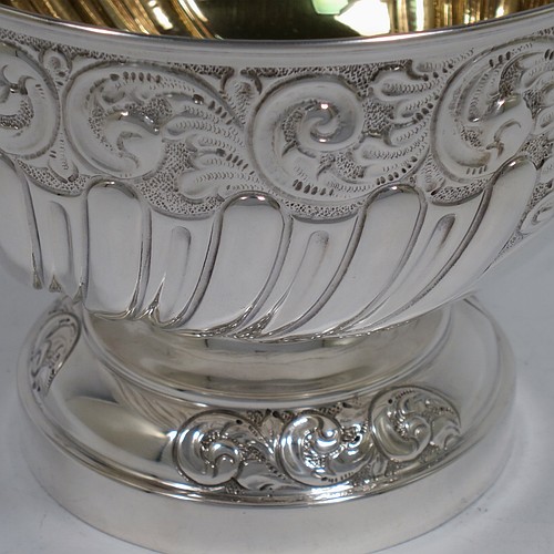 A very pretty Antique Edwardian Sterling Silver bowl, having a round body with hand-chased floral, scroll, and fluted decoration, an applied reeded border and a gold gilt interior, and all sitting on a pedestal foot with matching decoration. Made by William Hutton of Birmingham in 1906. The dimensions of this fine hand-made antique silver bowl are diameter 15 cms (6 inches), height 12 cms (4.75 inches), and it weighs approx. 247g (8 troy ounces). 