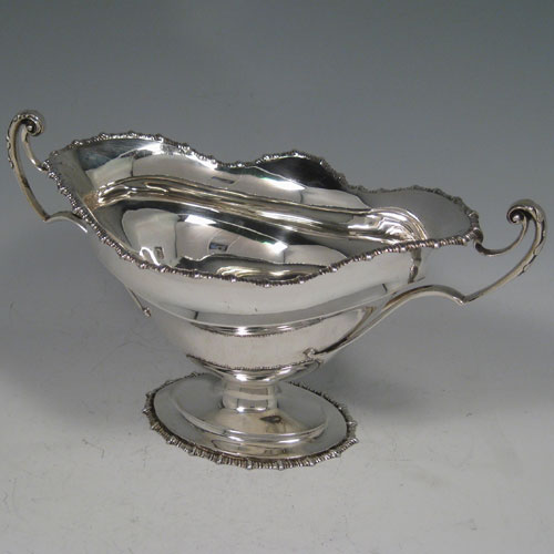 Antique Edwardian sterling silver two-handled oval bowl with gadroon edge and sitting on a pedestal foot. Made by James Dixon & Sons of Sheffield in 1905. The dimensions of this fine silver bowl are height 14 cms (5.5 inches), length 25.5 cms (10 inches), width 14 cms (5.5 inches), and it weighs approx. 13 troy ounces (403g).