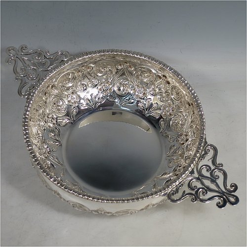 An Antique Edwardian Sterling Silver quaich style rose bowl, having a round bellied body with hand-chased floral decoration. an applied straight gadroon border, with two hand-pierced side-handles, and sitting on a flat base. Made by Peter Henderson Deere of London in 1909. The dimensions of this fine hand-made antique silver rose bowl in a quaich form are height 7 cms (2.75 inches), diameter 21.5 cms (8.5 inches), and it weighs approx. 669g (21.6 troy ounces).    