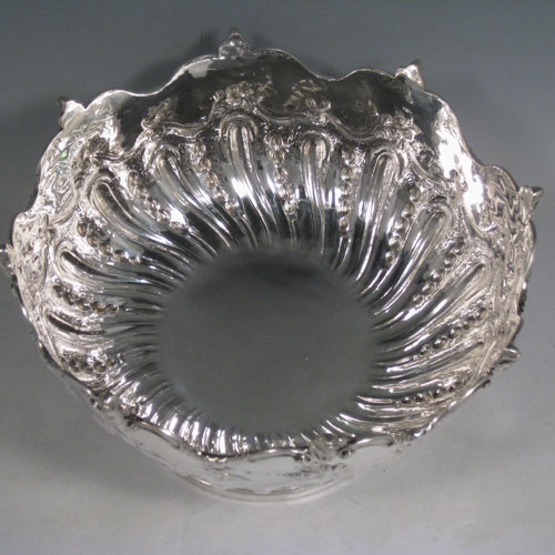 An Antique Victorian Sterling Silver Monteith style bowl, having a round body with an applied border and cast cherub heads, hand-chased floral and half swirl-fluted decoration, and sitting on a pedestal foot. Made in London in 1891. The dimensions of this fine hand-made antique silver Montieth bowl are diameter 24 cms (9.5 inches), height 14 cms (5.5 inches), and it weighs approx. 882g (28.5 troy ounces).   