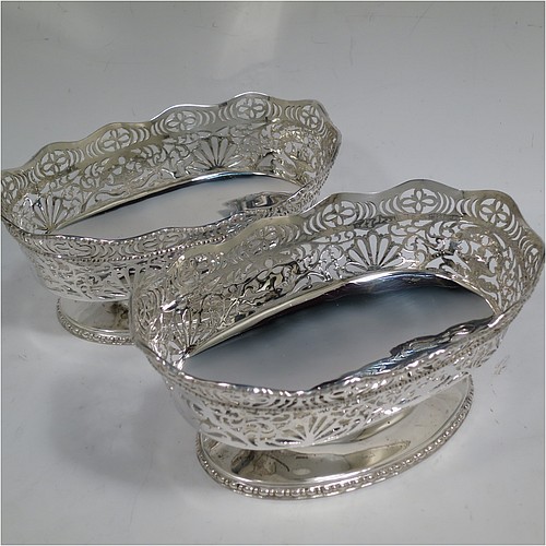 A very pretty pair of Sterling Silver table bowls, having oval bodies with hand-pierced floral and scroll decoration, with applied wavy bead-edged borders, and all sitting on pedestal feet. Made by S. Blanckensee and Sons Ltd., of Chester in 1930. The dimensions of these fine hand-made oval silver bowls are length 19 cms (7.5 inches), width 12.5 cms (5 inches), height 8 cms (3.25 inches), and they weigh a total of approx. 566g (18 troy ounces).   