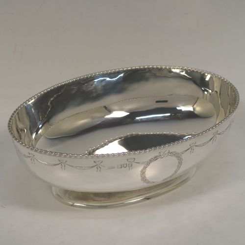 A very elegant Antique Sterling Silver bowl, having an oval body with hand-engraved neoclassical style engraving, an applied gadroon or rope-twist top border, and sitting on a pedestal foot. This beautiful antique silver oval bowl was made by Sir Richard Burbridge for Harrods of London in 1913. The dimensions of this fine hand-made silver bowl are height 7 cms (2.75 inches), length 20 cms (8 inches), width 13.5 cms (5.3 inches), and it weighs approx. 300g (9.7 troy ounces).  