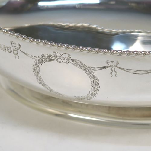 A very elegant Antique Sterling Silver bowl, having an oval body with hand-engraved neoclassical style engraving, an applied gadroon or rope-twist top border, and sitting on a pedestal foot. This beautiful antique silver oval bowl was made by Sir Richard Burbridge for Harrods of London in 1913. The dimensions of this fine hand-made silver bowl are height 7 cms (2.75 inches), length 20 cms (8 inches), width 13.5 cms (5.3 inches), and it weighs approx. 300g (9.7 troy ounces).  