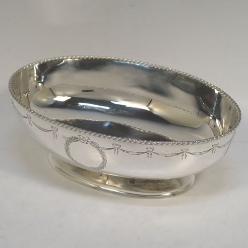 A very elegant Antique Sterling Silver bowl, having an oval body with hand-engraved neoclassical style engraving, an applied gadroon or rope-twist top border, and sitting on a pedestal foot. This beautiful antique silver oval bowl was made by Sir Richard Burbridge for Harrods of London in 1913. The dimensions of this fine hand-made silver bowl are height 7 cms (2.75 inches), length 20 cms (8 inches), width 13.5 cms (5.3 inches), and it weighs approx. 300g (9.7 troy ounces).  