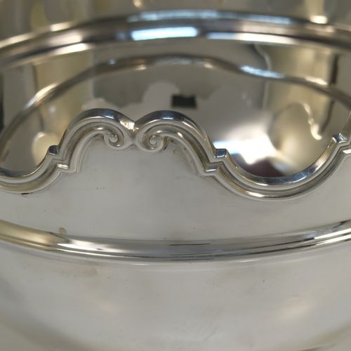 A very handsome Antique Sterling Silver Montieth style rose bowl, having a round plain body, an applied scroll top border above a reeded band, with two cast and hinged side-handles, and all sitting on a pedestal foot. This elegant antique silver rose bowl montieth was made by the Deakin Brothers of Sheffield in 1912. The dimensions of this fine hand-made antique silver rose Montieth bowl are height 17.5 cms (7 inches), diameter 21 cms (8.25 inches), and it weighs approx. 926g (29.9 troy ounces).   