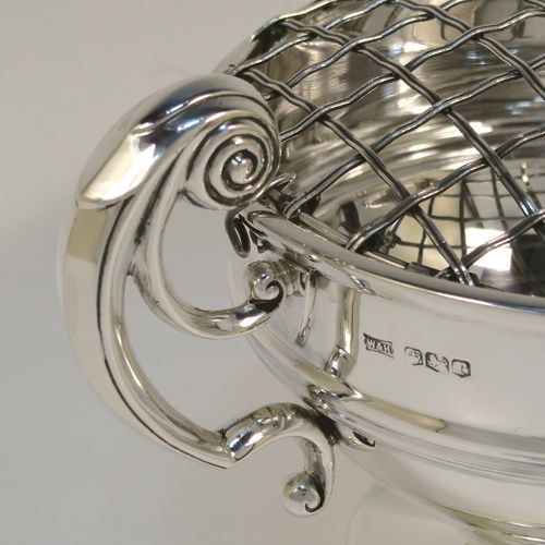 A handsome classical style Sterling Silver Rose bowl, having a round plain body with an applied reeded border, and a central applied band, with two flying scroll side handles, and sitting on a round pedestal foot, together with its original metal rose grill. This elegant silver rose bowl was made by Walker and Hall of Sheffield in 1934. The dimensions of this fine hand-made silver two-handled bowl are height (inc. handles) 11 cms (4.3 inches), diameter 12.5 cms (5 inches), and it weighs approx. 300g (9.7 troy ounces).   