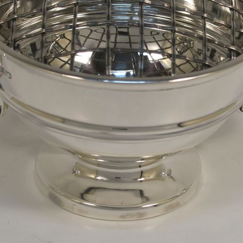 A handsome classical style Sterling Silver Rose bowl, having a round plain body with an applied reeded border, and a central applied band, with two flying scroll side handles, and sitting on a round pedestal foot, together with its original metal rose grill. This elegant silver rose bowl was made by Walker and Hall of Sheffield in 1934. The dimensions of this fine hand-made silver two-handled bowl are height (inc. handles) 11 cms (4.3 inches), diameter 12.5 cms (5 inches), and it weighs approx. 300g (9.7 troy ounces).   