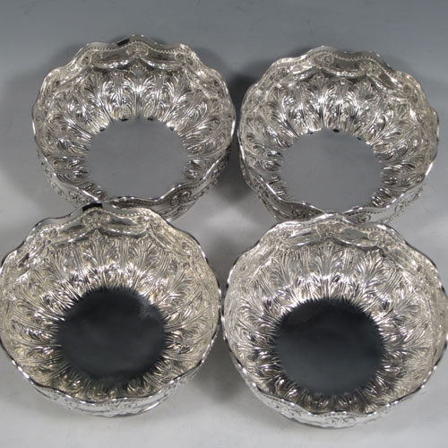 Antique Victorian sterling silver set of four bowls, having round bodies with hand-chased neoclassical style decoration showing bows, swags, and anthemion leaves, applied wavey gadroon borders, and sitting on hand-chased pedestal feet. Made by Martin and Hall of London in 1887. The dimensions of these fine hand-made silver bowls are diameter 13 cms (5 inches), height 6.5 cms (2.5 inches), and they weigh a total of 695g (22 troy ounces).