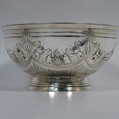 A very pretty Antique Victorian Sterling Silver bowl, having a round body with hand-chased swags of floral and scroll decoration over a lower band of vertical fluting, with an applied bead-edged border, and all sitting on a collet foot. Made by Edward Hutton of London in 1885. The dimensions of this fine hand-made antique silver bowl are diameter 11 cms (4.3 inches), height 6 cms (2.3 inches), and it weighs approx. 140g (4.5 troy ounces).    