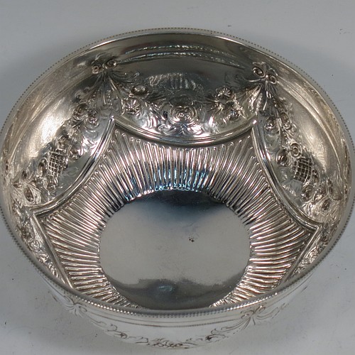 A very pretty Antique Victorian Sterling Silver bowl, having a round body with hand-chased swags of floral and scroll decoration over a lower band of vertical fluting, with an applied bead-edged border, and all sitting on a collet foot. Made by Edward Hutton of London in 1885. The dimensions of this fine hand-made antique silver bowl are diameter 11 cms (4.3 inches), height 6 cms (2.3 inches), and it weighs approx. 140g (4.5 troy ounces).    