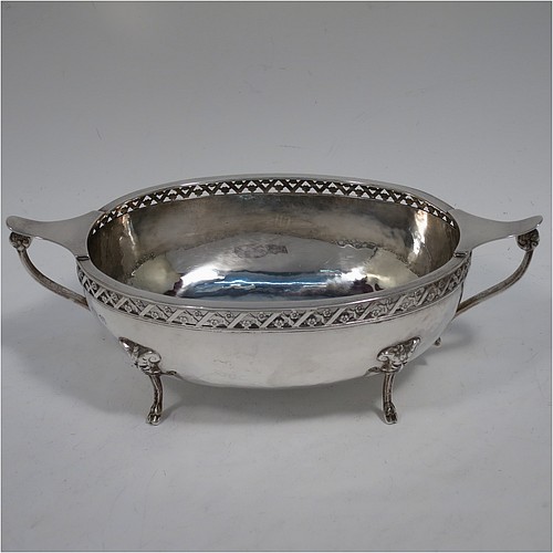 A very unusual and pretty pair of Arts and Crafts style Sterling Silver bowls, having oval bodies with hand-hammered decoration, with hand-pierced and floral borders, two scroll side-handles with flat thumb-pieces, and all sitting on four cast goat hoof feet. Made by A. E. Jones of Birmingham in 1921. The dimensions of these fine hand-made Arts and Crafts silver oval bowls are length 21 cms (8.25 inches), width 11 cms (4.3 inches), height 6.5 cms (2.5 inches), and they weigh a total of approx. 470g (15.2 troy ounces).    