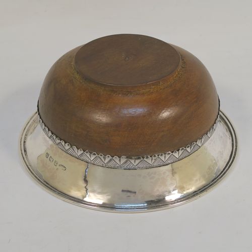 An Arts and Crafts style Sterling Silver & wood Mazer bowl, having a plain round plenished or hand-hammered body, mounted on an Oak base, and having an applied central Celtic style band. This beautiful silver Mazer bowl was made by A. E. Jones of Birmingham in 1928. The dimensions of this fine hand-made wood & silver Mazer bowl are diameter 14 cms (5.5 inches), and height 6.5 cms (2.5 inches). We cannot give a total weight because of the wooden base, but the gauge of silver used is very good.  