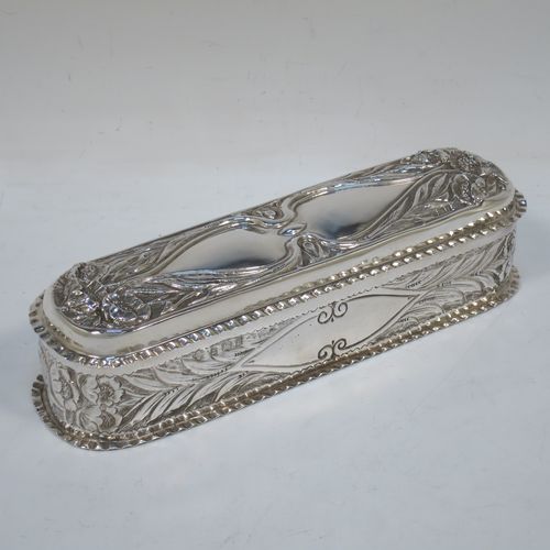 A bold and very pretty Antique Edwardian Sterling Silver Art Nouveau style table box, having a rounded rectangular body with hand-chased floral and scroll decoration, with crimped bead-edged borders and a gold-gilt interior, a hinged lid, and sitting on a flat base. Made by Nathan & Hayes of Birmingham in 1904. The dimensions of this fine hand-made antique silver Art Nouveau style box are length 20 cms (8 inches), width 6 cms (2.3 inches), height 5 cms (2 inches), and it weighs approx. 160g (5.2 troy ounces).   