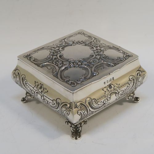 A very pretty Antique Edwardian Sterling Silver table box, having a square bellied body with hand-chased floral and scroll decoration, a hinged lid with matching decoration, a gold gilt interior, and sitting on four cast foliate and scroll feet. This beautiful antique silver box was made by Williams Ltd., of Birmingham in 1903. The dimensions of this fine hand-made silver box are 12.5 cms (5 inches) square, height 7.5 cms (3 inches), and it weighs approx. 328g (10.6 troy ounces).  