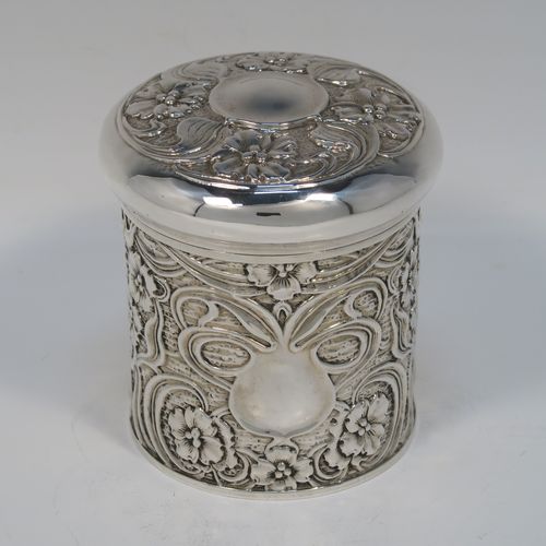 A very pretty Antique Edwardian Sterling Silver Art Nouveau style table box, having a round straight-sided body with hand-chased floral and scroll decoration, a pull-off lid with matching decoration and vacant central cartouche, a gold-gilt interior, and all sitting on a flat base. This beautiful Art Nouveau silver box was made by Synyer and Beddoes of Birmingham in 1903. The dimensions of this fine hand-made antique silver Art Nouveau style box are height 9 cms (3.5 inches), diameter 8 cms (3.25 inches), and it weighs approx. 130g (4.2 troy ounces).   