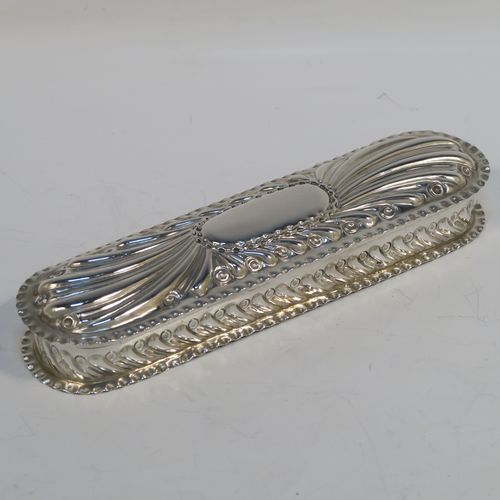 A beautiful Antique Victorian Sterling Silver Art Nouveau style table box, having a rounded rectangular body with hand-chased fluted and scroll decoration, with crimped bead-edged borders and a gold-gilt interior, a hinged lid with a vacant oval cartouche, and sitting on a flat base. This pretty antique silver box was made by Gibson and Langland of London in 1898. The dimensions of this fine hand-made antique silver Art Nouveau style box are length 17.5 cms (7 inches), width 5 cms (2 inches), height 2.5 cms (1 inch), and it weighs approx. 142g (4.6 troy ounces).   