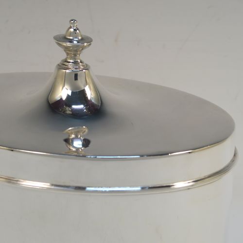 A large and very handsome Antique Edwardian Silver Plated table box, having a very plain oval body with straight sides, a hinged lid with a cast urn-shaped finial, and all sitting on a flat base. This elegant antique table box was made in ca. 1910. The dimensions of this fine hand-made antique silver-plated table box are height 17 cms (6.75 inches), width 17 cms (6.75 inches), and depth 10 cms (4 inches).  