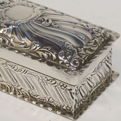 A beautiful Antique Victorian Sterling Silver table box, having a rectangular body with hand-chased floral and scroll and floral decoration, a hinged lid with a vacant central cartouche and matching decoration, and sitting on a flat base. This pretty antique silver box was made by Goldsmiths and Silversmiths of London in 1900. The dimensions of this fine hand-made antique sterling silver box are length 10 cms (4 inches), width 5 cms (2 inches), height 3.5 cms (1.25 inches), and it weighs approx. 97g (3 troy ounces).   