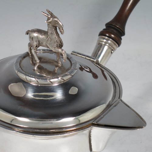 An Antique Georgian Sterling Silver brandy saucepan warmer, having a plain round tapering straight-sided body, a hinged domed lid with a cast goat finial and a hinged sparrow-beak spout, an original wood turned handle, with a gold-gilt interior, and all sitting on a reeded collet foot. Made by Joseph Angell I of London in 1821. The dimensions of this fine hand-made brandy saucepan warmer are height (inc. finial) 13 cms (5 inches), length (inc. handle) 22 cms (8.75 inches), and it weighs approx. 310g (10 troy ounces).   