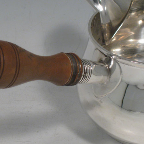 Antique Edwardian sterling silver brandy saucepan warmer, having a plain round baluster body, a sparrow-beak spout, an original wood turned handle, and sitting on a collet foot. Made in Birmingham in 1910. Height (inc. handle) 9 cms (3.5 inches), length (inc. handle) 18 cms (7 inches). Weight approx. 125g (4 troy ounces).