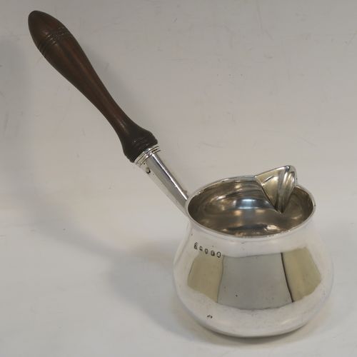 A handsome Antique Georgian Sterling Silver brandy saucepan warmer, having a plain round bellied body, a sparrow-beak spout, an original wood turned handle, and sitting on a flat base. This elegant antique silver brandy or sauce warmer was made by Thomas Oliphant of London in 1801. The dimensions of this fine hand-made silver sauce or brandy warmer are height (inc. handle) 15 cms (6 inches), length (inc. handle) 19 cms (7.5 inches), diameter of main body 9 cms (3.5 inches), and it weighs approx. 150g (4.8 troy ounces).   