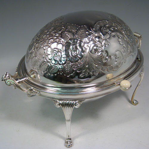 Antique Victorian silver-plated breakfast dish with revolving lid, original liners, and having hand-chased florally decorated body, sitting on four cast fluted feet. Made by Harrison Brothers and Howson of Sheffield in ca. 1870. Height 22 cms (8.5 inches), length 36 cms (14 inches), width 23 cms (9 inches).