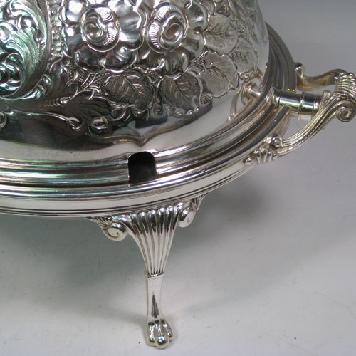 Antique Victorian silver-plated breakfast dish with revolving lid, original liners, and having hand-chased florally decorated body, sitting on four cast fluted feet. Made by Harrison Brothers and Howson of Sheffield in ca. 1870. Height 22 cms (8.5 inches), length 36 cms (14 inches), width 23 cms (9 inches).