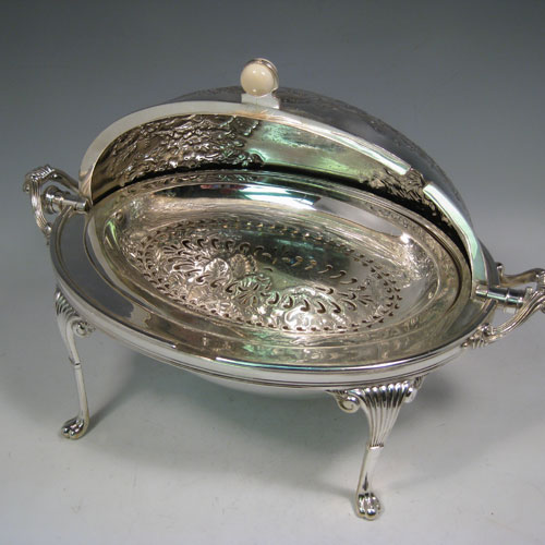 Antique Victorian silver-plated breakfast dish with revolving lid, original liners, and having hand-chased florally decorated body, sitting on four cast fluted feet. Made by Harrison Brothers and Howson of Sheffield in ca. 1870. Height 22 cms (8.5 inches), length 36 cms (14 inches), width 23 cms (9 inches).