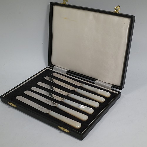 A Sterling Silver and Mother-of-Pearl handled set of six butter or tea knives, having plain mother-of-pearl handles, and plain silver parallel sided and rounded-end blades, all in their original cream satin and black velvet-lined presentation box. Made by Charles Boyton & Sons of Sheffield in 1966. The dimensions of this fine hand-made set of tea or butter knives are length of each knife 15 cms (6 inches).