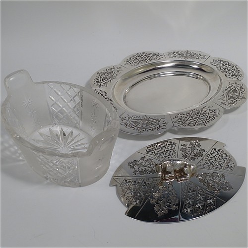 An Antique Victorian Silver Plated butter dish and cover, having an oval crystal body with panels of hand-cut and frosted decoration, a lift-off hand-engraved lid with a cast cow finial, and all sitting on a hand-engraved and pierced lobed oval dish. Made in ca. 1880. The dimensions of this fine hand-made antique silver plated butter dish are height 8 cms (3 inches), length 23 cms (9 inches), and width 19 cms (7.5 inches).    