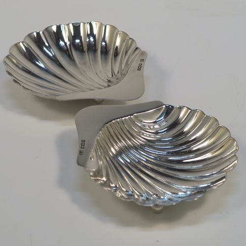 A pretty Antique Sterling Silver pair of butter shells, having hand-chased scalloped bodies, plain shaped thumb-pieces, and both sitting on three ball feet. These beautiful silver shell butter dishes were made by the Atkins Brothers of Sheffield in 1915. The dimensions of these fine hand-made antique silver butter dishes are length 12 cms (4.75 inches), width 8 cms (3.25 inches), and they have a total weight of approx. 71g (2.3 troy ounces).   