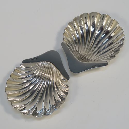 A pretty Antique Sterling Silver pair of butter shells, having hand-chased scalloped bodies, plain shaped thumb-pieces, and both sitting on three ball feet. These beautiful silver shell butter dishes were made by the Atkins Brothers of Sheffield in 1915. The dimensions of these fine hand-made antique silver butter dishes are length 12 cms (4.75 inches), width 8 cms (3.25 inches), and they have a total weight of approx. 71g (2.3 troy ounces).   