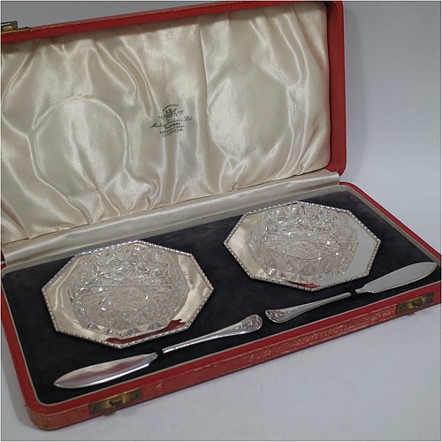 A very pretty Sterling Silver pair of Art Deco style butter dishes, having octagonal bodies with applied bead-edged borders, with removable hand-cut crystal dishes, and a pair of silver butter servers, all sitting in their original cream satin and black velvet-lined presentation box. Made by the Adie Brothers of Birmingham in 1936. The dimensions of this fine hand-made set of silver butter dishes and servers are width 11 cms (4.25 inches), height 2.5 cms (1 inch), with a total weight of approx. 145g (4.7 troy ounces).    