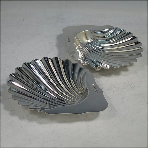 An Antique Victorian Sterling Silver pair of butter shells, having hand-chased scalloped bodies, plain shaped thumb-pieces, and both sitting on three ball feet. All made by Mappin & Webb of Sheffield in 1901. The dimensions of these fine hand-made antique silver butter dishes are length 12 cms (4.75 inches), width 9.5 cms (3.75 inches), height 2 cms (0.75 inches), and they have a total weight of approx. 146g (4.7 troy ounces).    