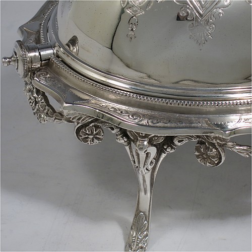 An Antique Victorian Silver Plated revolving top butter dish, having a hand-chased oval body with floral decoration and bead-edged border, a frosted glass removable internal liner, and sitting inside a cast frame with floral swags and four cast feet. All made in ca. 1880. The dimensions of this fine hand-made antique silver-plated butter dish are length 20 cms (8 inches), height 13 cms (5 inches), and width 15 cms (6 inches).    