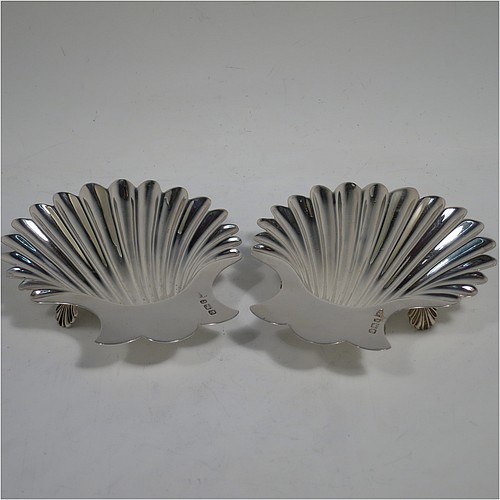 A very handsome Antique Victorian Sterling Silver pair of butter shells, having hand-chased scalloped bodies, plain shaped thumb-pieces, and both sitting on three cast shell-shaped feet. All made by Walker and Hall of Sheffield in 1897/99. The dimensions of these fine hand-made antique silver butter dishes are length 13 cms (5 inches), width 11 cms (4.25 inches), height 2.5 cms (1 inch), and they have a total weight of approx. 163g (5.25 troy ounces).    