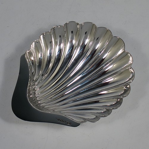 An Antique Sterling Silver pair of butter shells, having hand-chased scalloped bodies, plain shaped thumb-pieces, and both sitting on three ball feet. All made by Henry Atkins of Sheffield in 1913. The dimensions of these fine hand-made antique silver butter dishes are length 12 cms (4.75 inches), width 10 cms (4 inches), height 2.5 cms (1 inch), and they have a total weight of approx. 113g (3.6 troy ounces).    