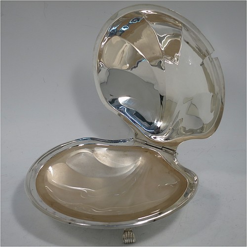 A very handsome and unusual Sterling Silver covered butter shell dish, having a hand-chased scalloped body, a hinged cover with a cast thumb-piece and knife slot, with a ring side-handle, a frosted cut removable liner, and all sitting on three cast reeded feet. Made by Henry Matthews of Birmingham in 1922. The dimensions of this fine hand-made silver butter dish shell are length 16.5 cms (6.5 inches), width 14 cms (5.5 inches), and it weighs approx 179g (5.7 troy ounces).    